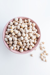 Roasted white chickpeas in a bowl on white background, top view.