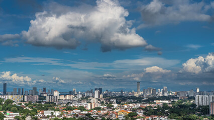 Fototapeta premium Panorama of a modern city. Urban buildings surrounded by green vegetation. Towers of skyscrapers against a blue sky and clouds. Georgetown's cityscape. View from the height. Malaysia. Penang.