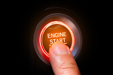 The driver's hand is pressing the car start button. Concept of transportation and technology	