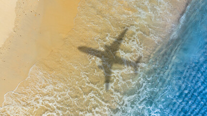 Aerial view of shadow passenger plane silhouette and sandy beach blue sea with waves at sea beach summer vacation sea travel concept	