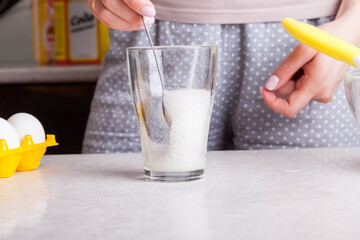 Making cupcakes at home. A woman prepares Easter cakes in the kitchen by whipping soda in a glass.