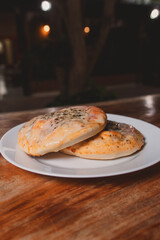 Small pizzas on a white plate on a wooden table.
