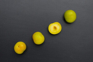 Fresh green plum fruit on dark background.