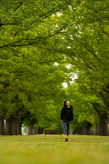 Obraz premium Front view of a woman admiring the beauty of Elms trees on a sunny day in Camperdown, Victoria, Australia