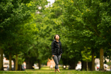 Front view of a woman admiring the beauty of Elms trees on a sunny day in Camperdown, Victoria,...
