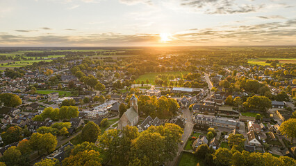 Sunset illuminating dutch village surrounded by colorful autumn trees and green fields