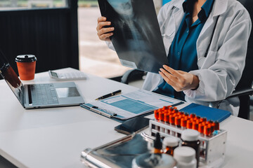 Positive doctor working on laptop in medical office, portrait.