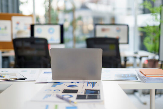 Laptop standing on desk with graphs and charts in modern office