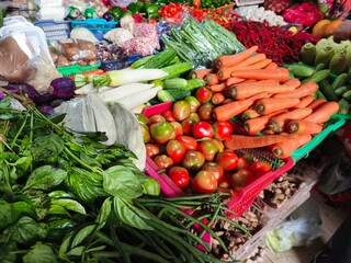Colorful array of fresh vegetables, including carrots, tomatoes, and greens, showcasing the lively atmosphere of a local market.
