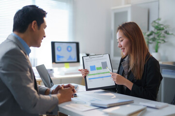 Asian businesspeople analyzing marketing data discussing strategy in office