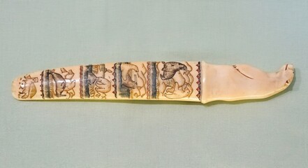 Chukchi dagger made of walrus tusk, Intricately carved walrus ivory knife with animal motifs displayed on a soft background