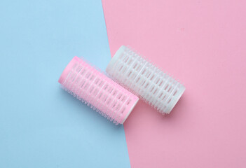Plastic hair curlers on pink blue background