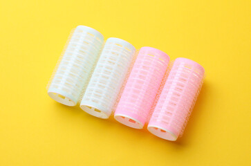 Plastic hair curlers on yellow background
