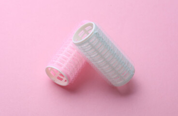 Plastic hair curlers on pink background