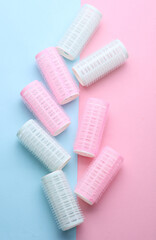 Plastic hair curlers on pink blue background