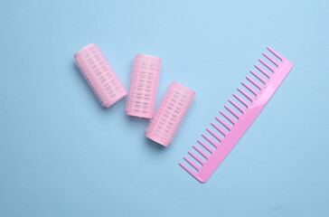 Plastic curlers and hair comb on blue background. Flat lay