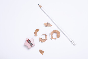 White sharpened pencil and shavings with sharpener on white background