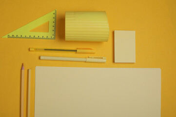 Sheets of paper with school stationery on yellow background. Monochrome photography. Flat lay....