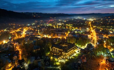 Obraz premium Zakopane: Widok na miasto rozświetlone lampami o poranku, jesienią z drona