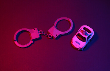 Toy handcuffs and police car in red blue neon light