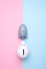 Piggy bank and space shuttle on blue pink background. Startup idea