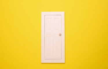 Miniature wooden door on yellow background