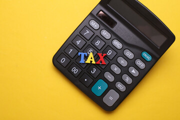 Obraz premium Calculator with word tax on yellow background