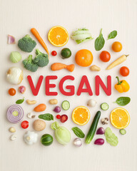 Naklejka premium Vibrant vegetables and fruits arranged to spell VEGAN create fresh, healthy vibe