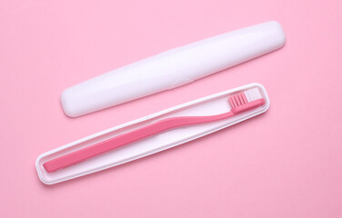 Plastic case with toothbrush on pink background