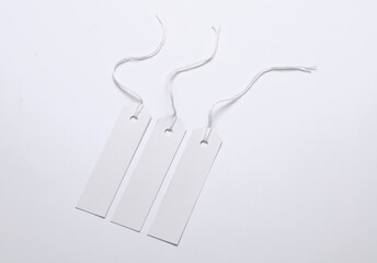 White paper tags on strings on white background