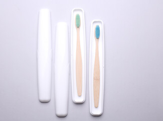 Plastic cases with wooden toothbrushes on gray background