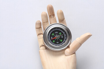 Wooden puppet hand with Metal tourist compass on white background