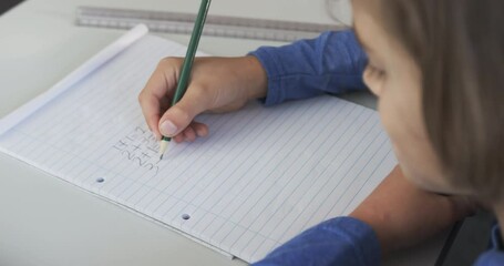 Practicing handwriting, child writing in notebook in school classroom