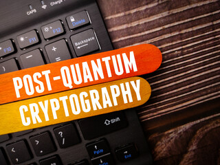 Black keyboard with the word POST QUANTUM CRYPTOGRAPHY on a wooden background