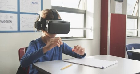 In school, child using VR headset while writing in notebook at desk - Powered by Adobe