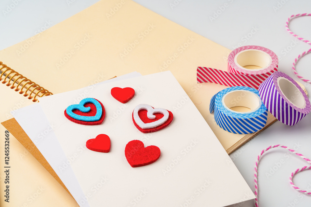 Poster crafting colorful heart decorations with felt and tape on a blank notebook during a creative session
