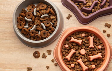 Slow feeder dog bowls with various dry food on wooden table