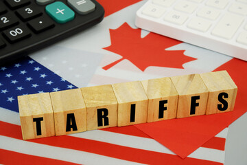 Tariffs between the United States and Canada. USA and Canadian flags and wooden cubes with word tariffs and calculators.
