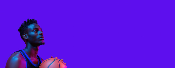Athlete holding a basketball against a vibrant purple background in focused neon lighting