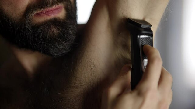 Man shaving his armpit hair . Shaving with trimmer	