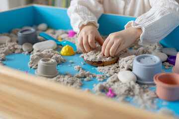 Children activity with kinetic sand for motor and sensory development. Toddler play therapy with colorful toys on sandbox..