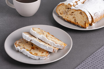 Delicious homemade stollen bread displayed on a plate with powdered sugar and chopped nuts in festive setting