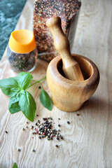 Wooden Mortar and Pestle with Basil and Peppercorns on a Rustic Kitchen Counter