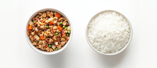 Top down view of white bowl with cooked rice mixed with colorful vegetables and meat beside a plain white bowl of rice on a white background