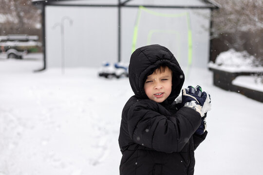 Young boy in winter coat getting ready to throw snowball