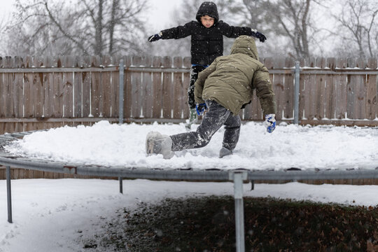Kids playing on a snowy trampoline in a winter backyard scene