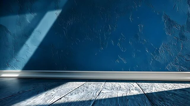 A simple interior shot featuring a textured blue wall, a light wooden floor, and a white baseboard trim.