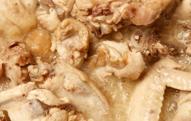 A close up of chicken meat in a pot of boiling water