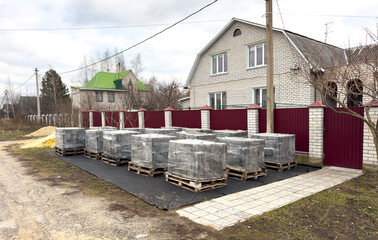 A row of boxes are stacked on a black mat in front of a house