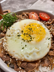 A bowl of yakiniku beef rice with sunny side up